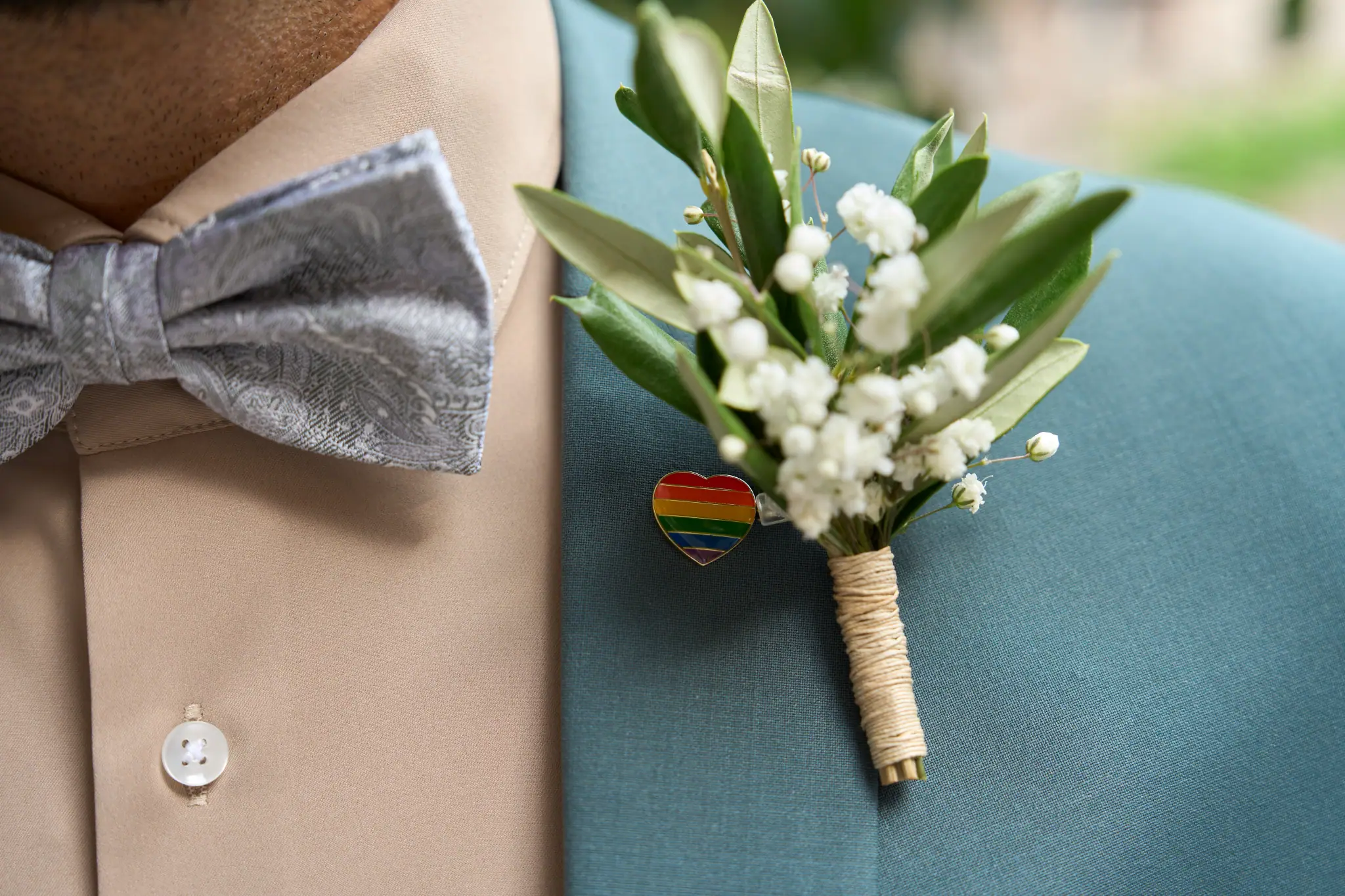 Regenbogensymbol in Form eines angesteckten Herzens am Hochzeitsanzug.